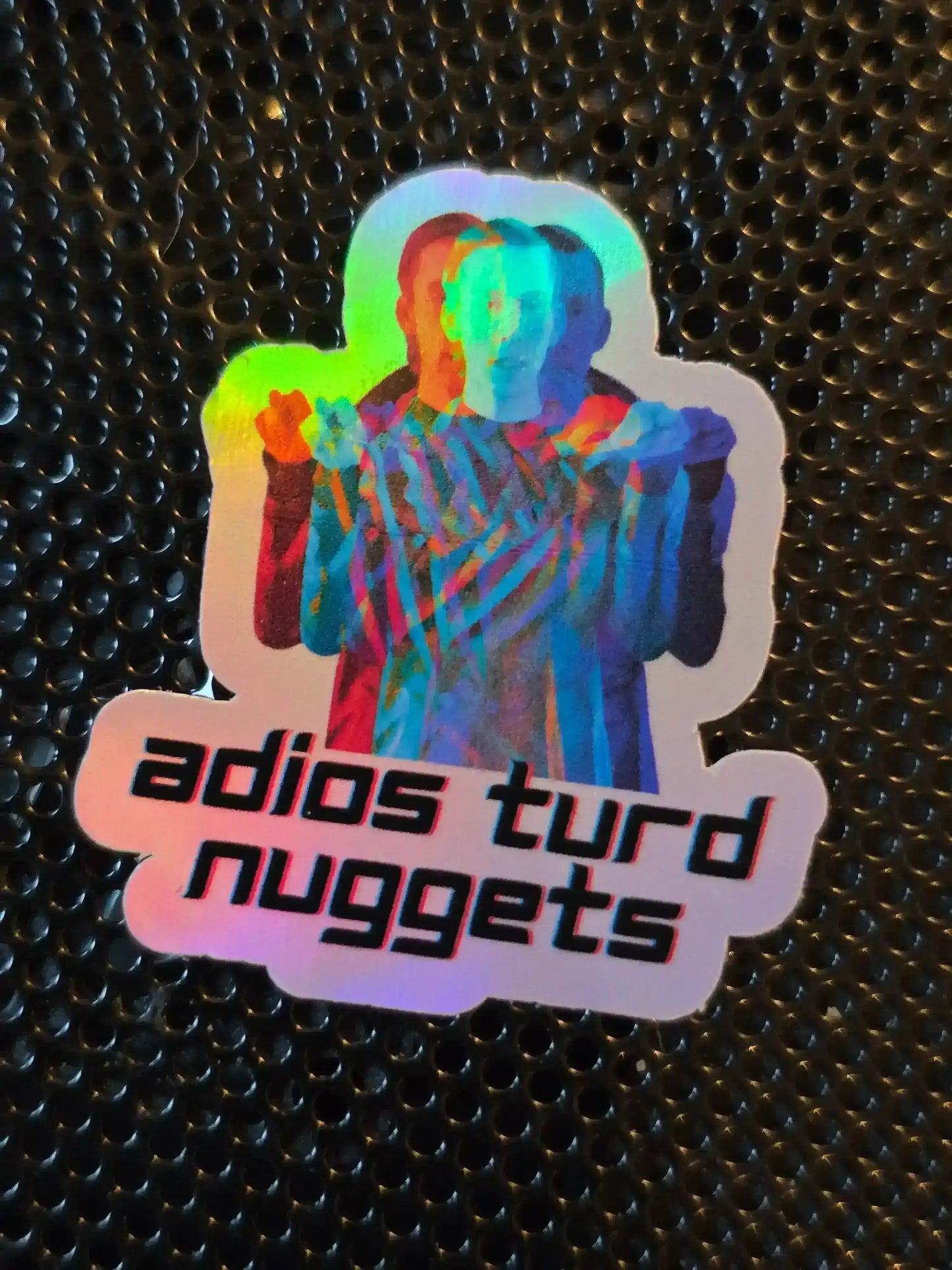 Holographic Cady Creations sticker with colorful figure and 'adios turd nuggets' text on black