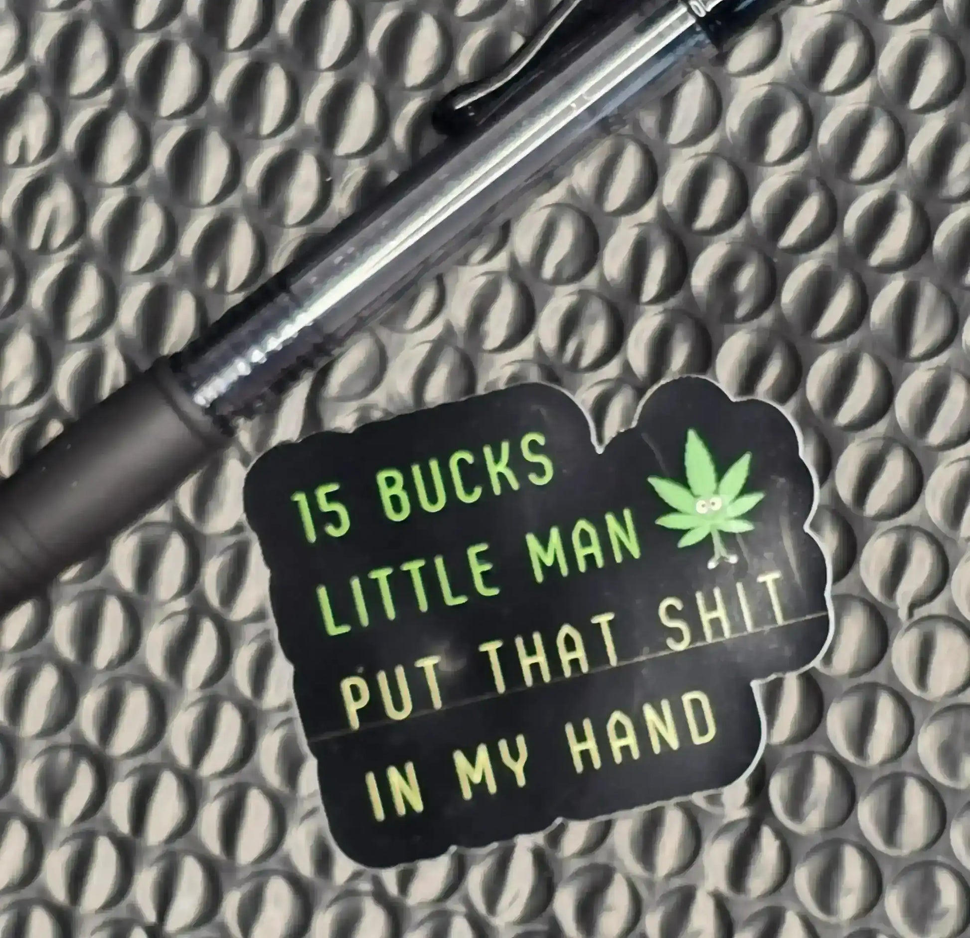 Cady Creations sticker with green text, cartoon leaf, and a pen on a textured surface