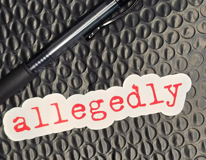 Allegedly sticker with red text on white, next to black pen on textured surface, Cady Creations