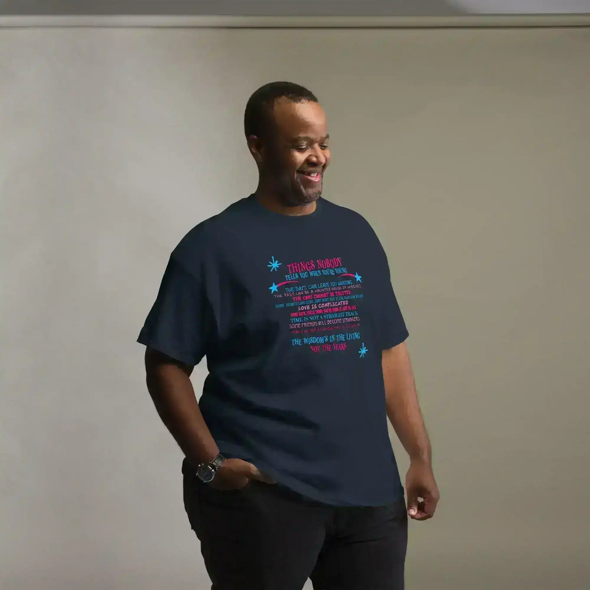 Man wearing navy Cady Creations graphic tee with colorful text and stars on neutral background