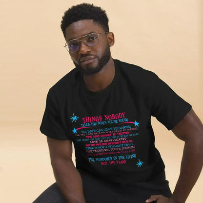 Man wearing Cady Creations unisex black graphic tee with colorful text, beige background