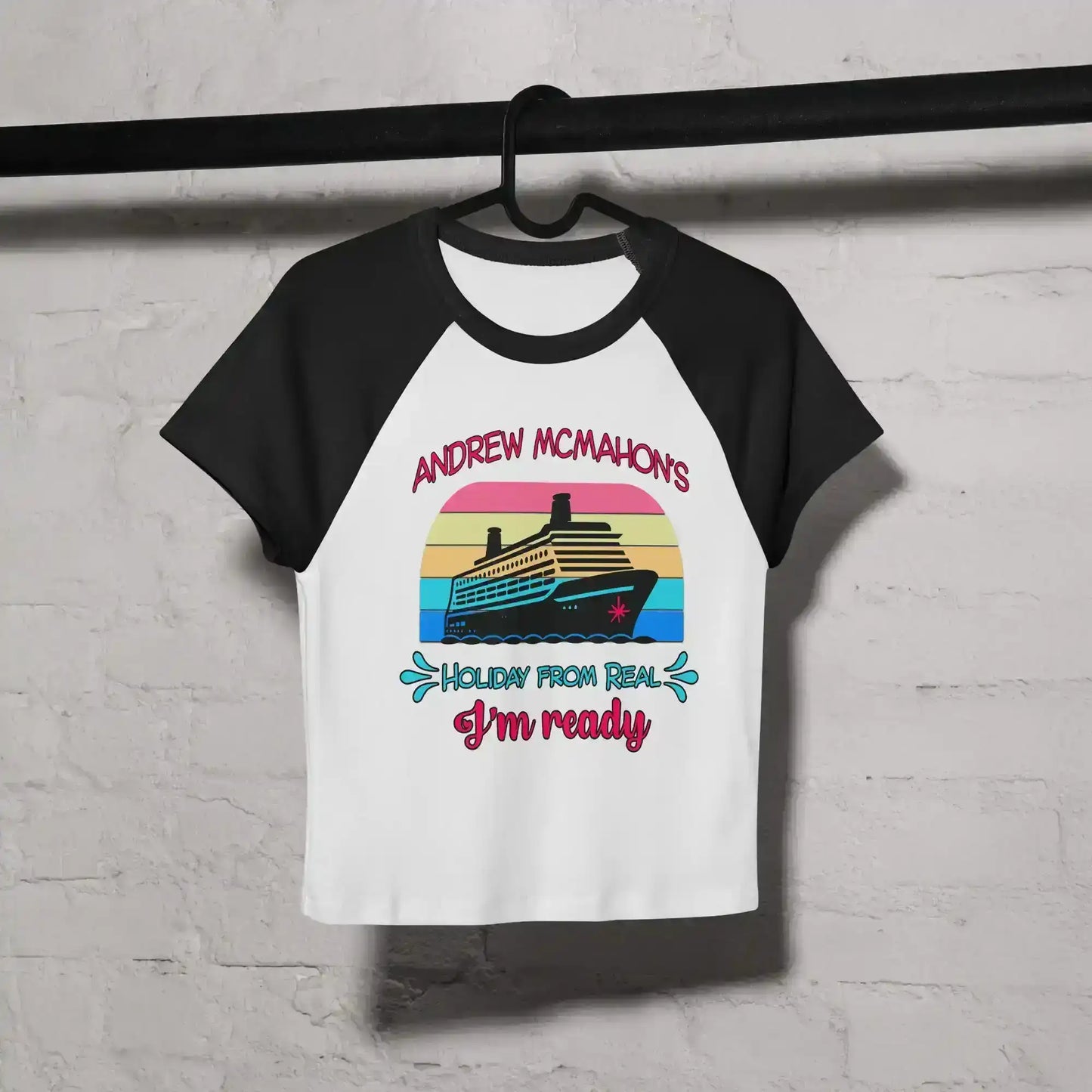 Women's black and white raglan baby tee with cruise ship graphic and colorful text, hung on hanger