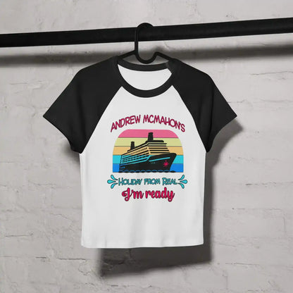 Women's black and white raglan baby tee with cruise ship graphic and colorful text, hung on hanger